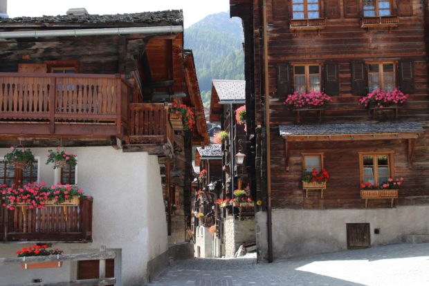 Zahlreiche, alte Chalets in Griments, geschmückt mit roten Geranien