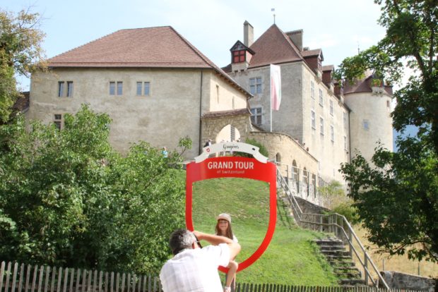 Ein Mann fotografiert seine Tochter im Grand Tour Fotorahmen vor dem Schloss Greyerz 