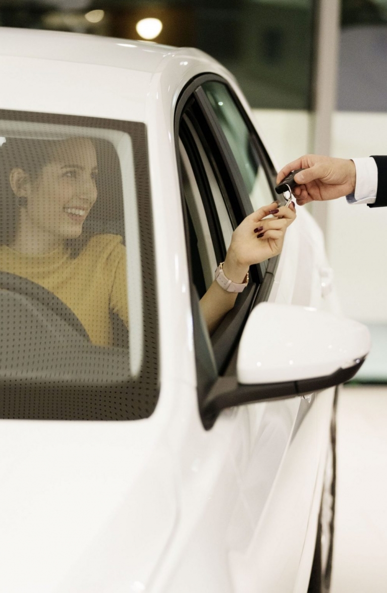 Einer Frau wird der Schlüssel ihres Autos übergeben.