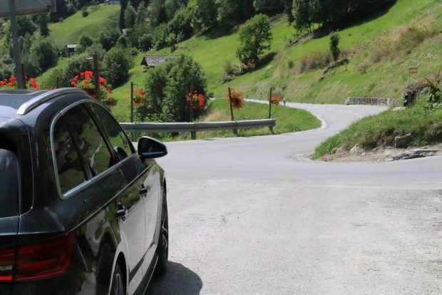 Une S4 pose devant un virage orné de géraniums En arrière-plan, on aperçoit Grimentz 